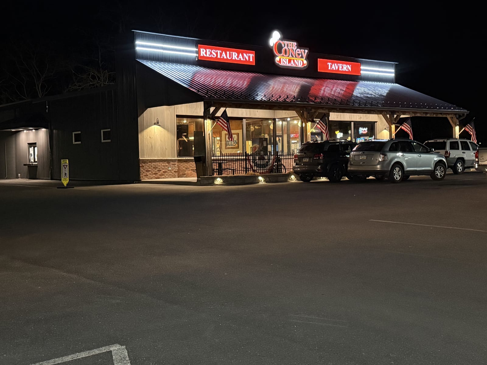 The Coney Island in Pottsville, PA lit up at night, with cars parked out front.