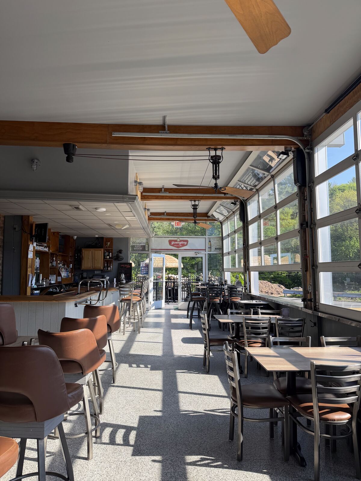 Seating on the four-season patio at The Coney Island in Pottsville, PA — tables under roll-up glass garage doors, year-round dining.