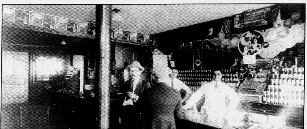 Interior of 215 N. Centre St., c. 1920 — Sarantos Palles in white behind the counter, customers at the soda fountain.