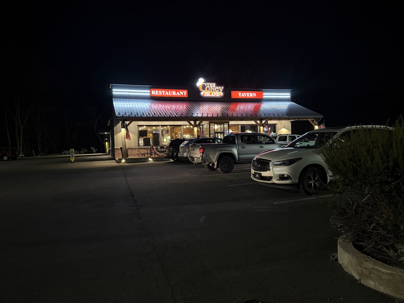The Coney Island in Pottsville, PA lit up at night, with cars parked out front.